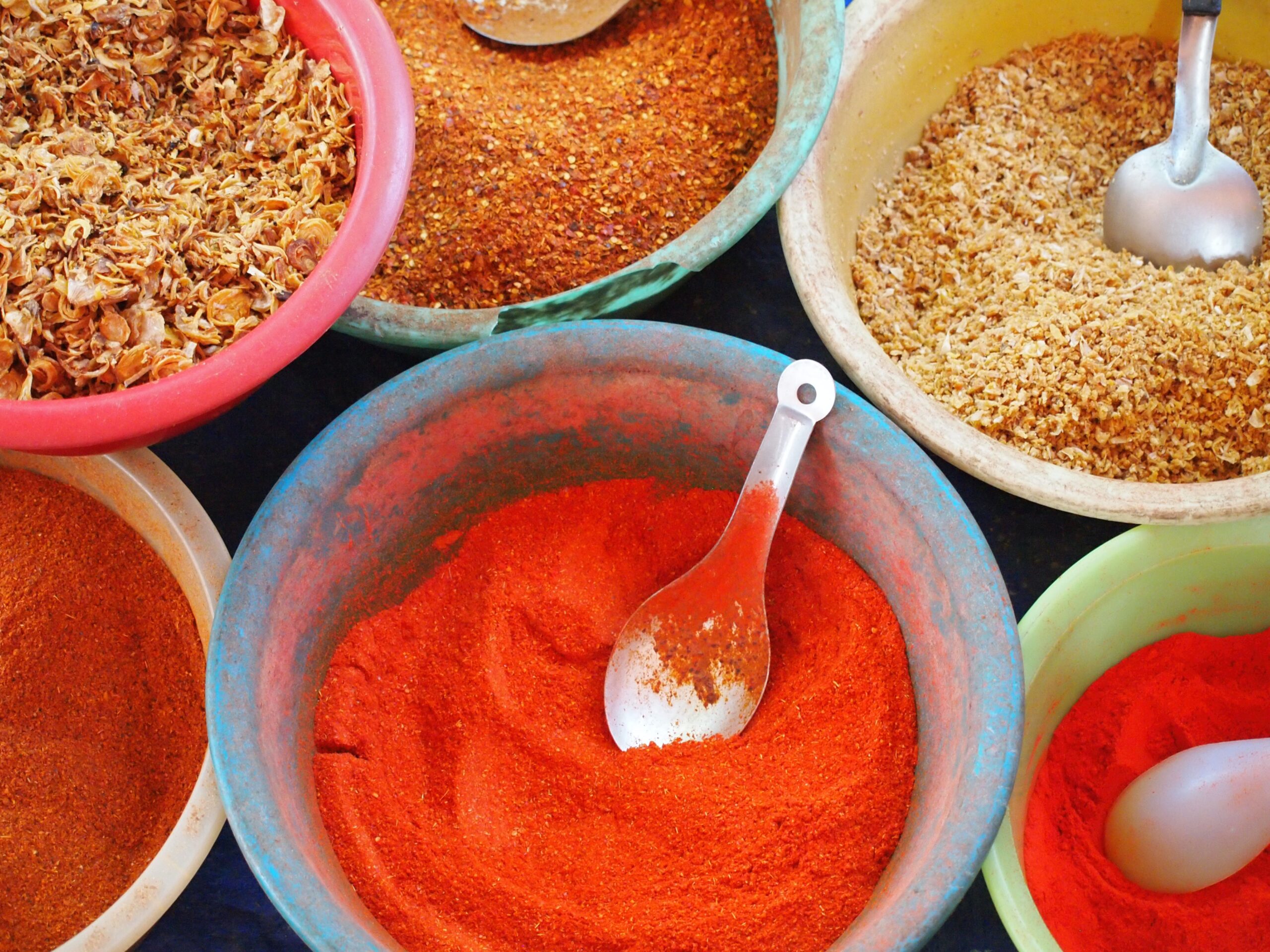 bowls of various spices and spoons on a table