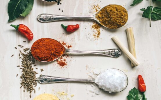 five gray spoons filled with assorted-color powders near chilli