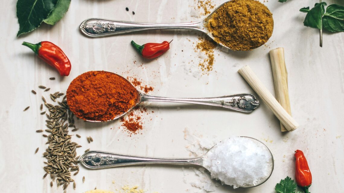 five gray spoons filled with assorted-color powders near chilli