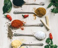 five gray spoons filled with assorted-color powders near chilli