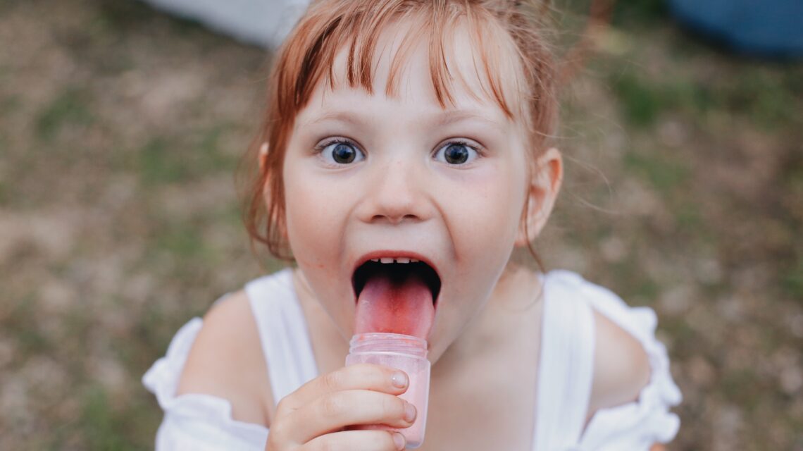 girl licking jar selective focus photography