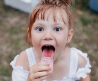 girl licking jar selective focus photography