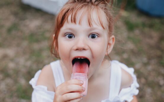 girl licking jar selective focus photography