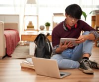 Young student studying online with tablet and laptop at home, representing remote learning and digital education