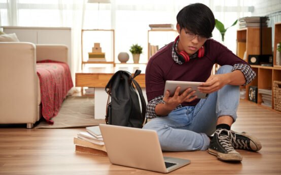 Young student studying online with tablet and laptop at home, representing remote learning and digital education