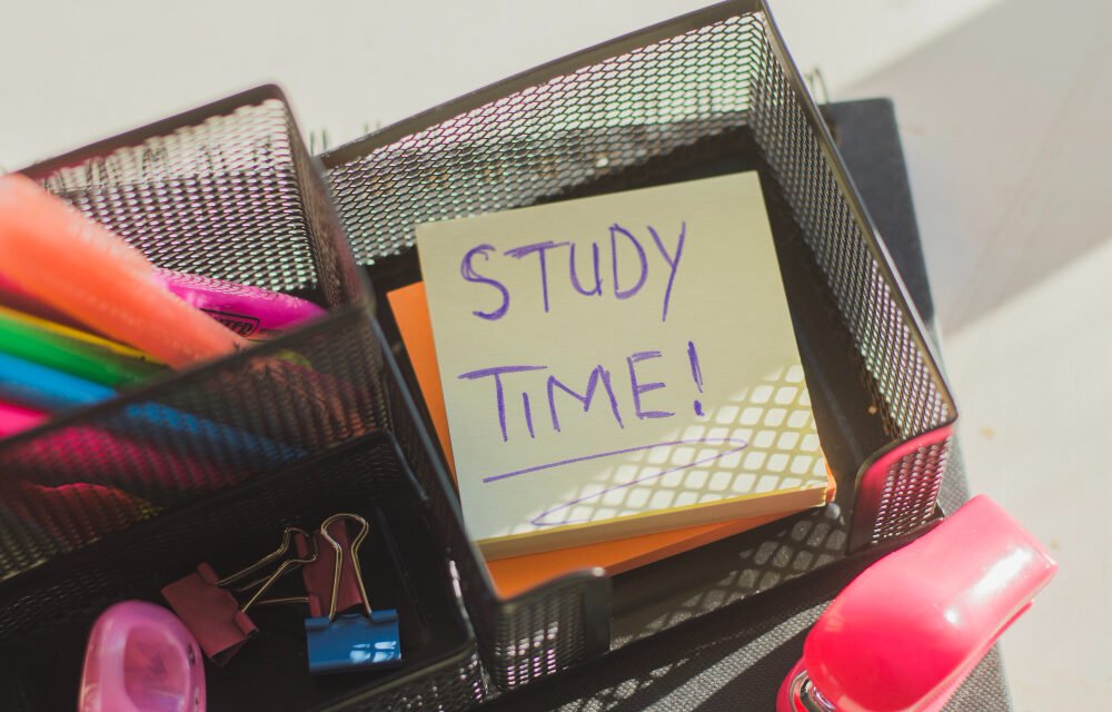 Top view of study desk organizer with highlighters, clips, and a sticky note reminding 'Study Time' for motivation and productivity.