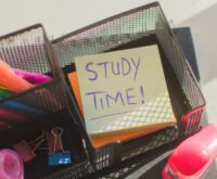 Top view of study desk organizer with highlighters, clips, and a sticky note reminding 'Study Time' for motivation and productivity.
