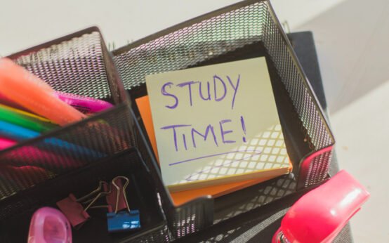Top view of study desk organizer with highlighters, clips, and a sticky note reminding 'Study Time' for motivation and productivity.