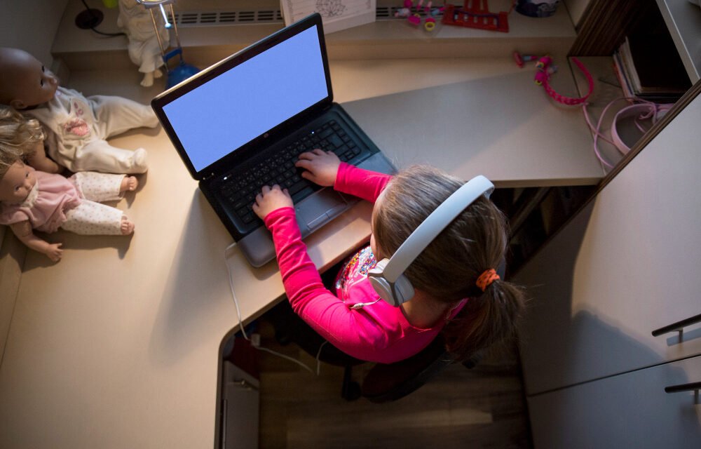 Child learning online at home with headphones and laptop, representing digital education and remote learning for kids