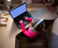 Child learning online at home with headphones and laptop, representing digital education and remote learning for kids