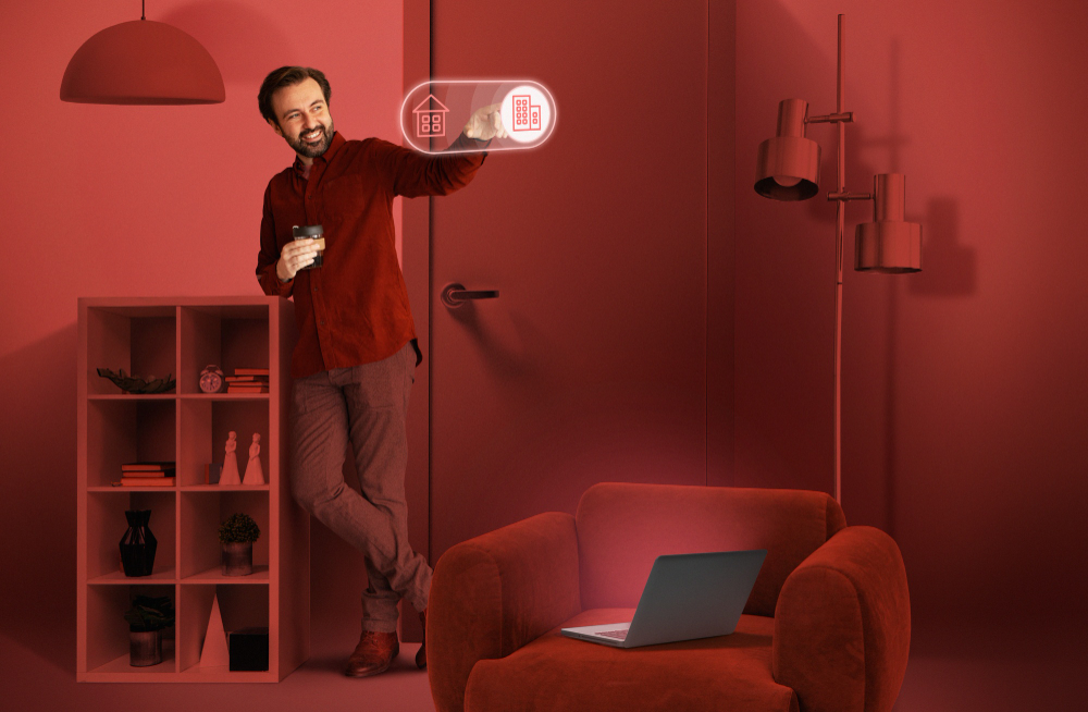 Man interacting with futuristic smart home interface while standing in a red-toned modern living room with a laptop on an armchair