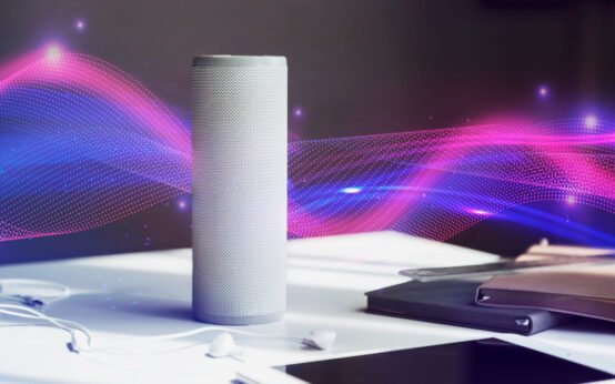 Smart voice assistant speaker on a desk with colorful sound wave graphics symbolizing voice interaction and AI technology