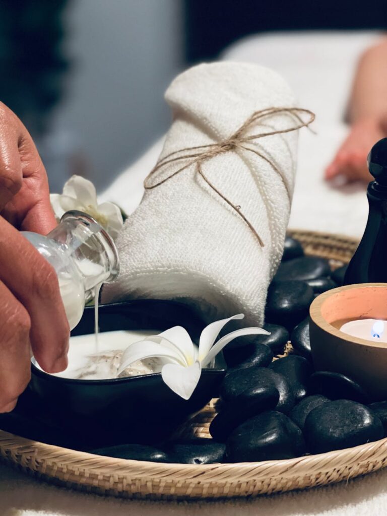 A detailed shot of white frangipani flowers and smooth black massage stones ready for a spa treatment.