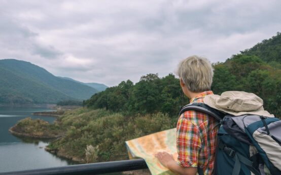 A couple planning their solar eclipse vacation route with a map spread across the hood of their car in the mountains.