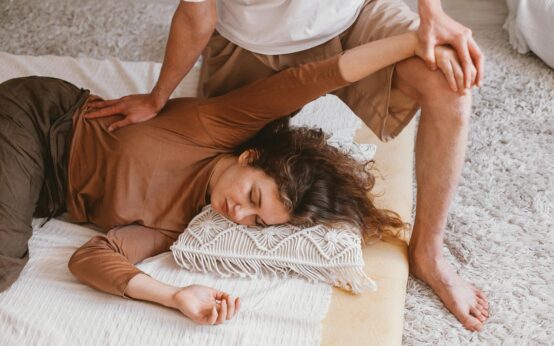 A therapist performs a traditional Balinese massage on a client's back in a serene spa.