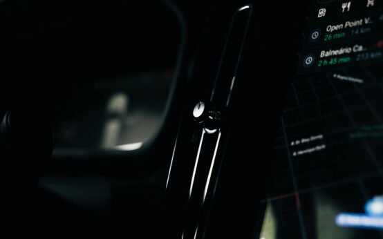 A futuristic view from inside an autonomous vehicle showing a holographic dashboard and city lights.