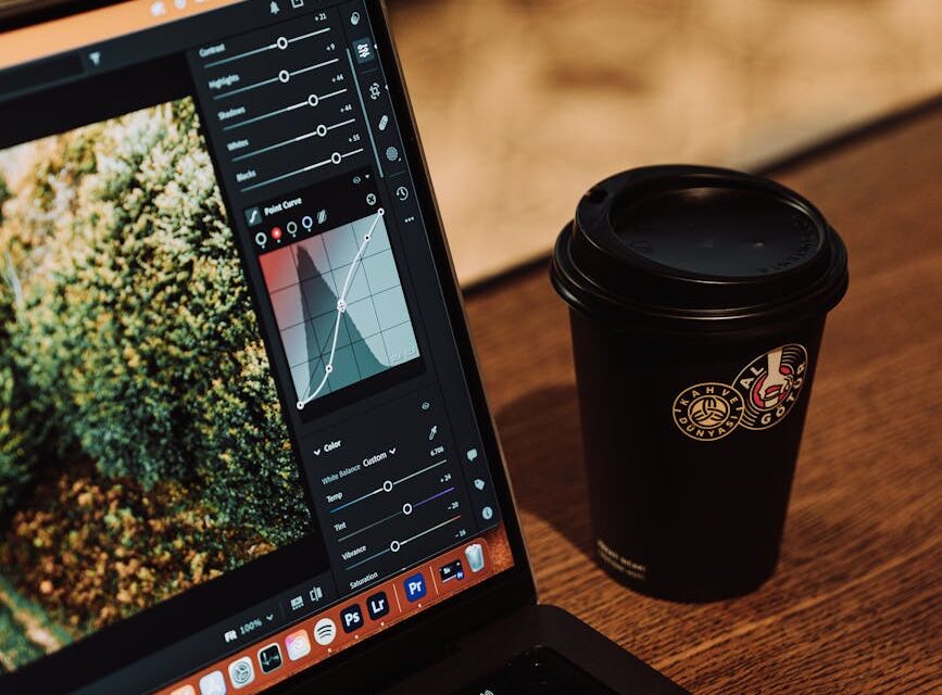A creative professional editing a photograph on a modern laptop in a cozy cafe setting.