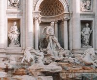 The illuminated Trevi Fountain in Rome at night, with water cascading over massive baroque statues.