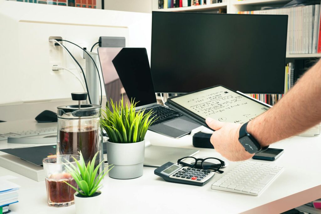 A freelancer's productive and organized desk setup featuring a laptop, calendar, and a cup of coffee.