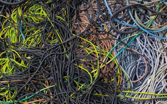Glowing blue fiber optic cables running through a dark server rack in a data center.