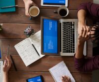 A person and a humanoid robot collaborating over a tablet in a bright, modern office setting.