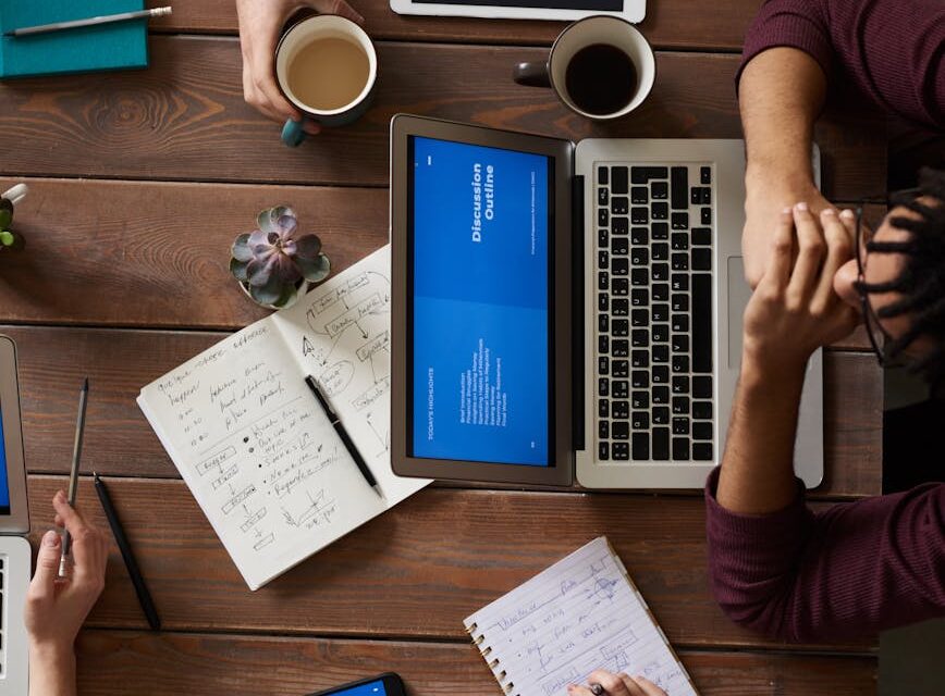 A person and a humanoid robot collaborating over a tablet in a bright, modern office setting.