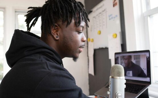 A voice over artist speaking into a professional microphone in a home studio setup.