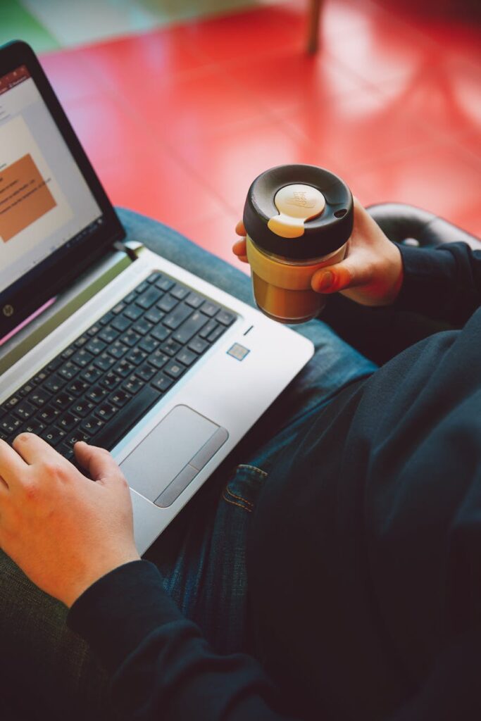 A person's hands typing on a laptop with financial charts and graphs visible on the screen.