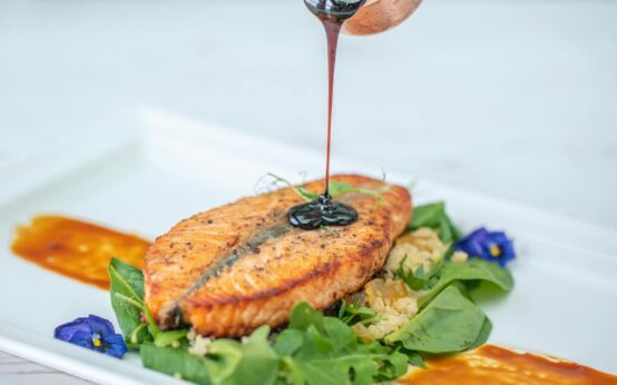 A beautifully arranged plate featuring grilled salmon, a handful of fresh blueberries, and a side of wilted spinach, representing a healthy anti-inflammatory meal.