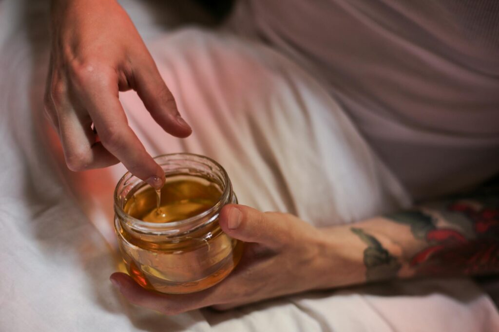 A pair of hands holding an open glass jar filled with vibrant red kimchi, showing the texture of the fermented cabbage.