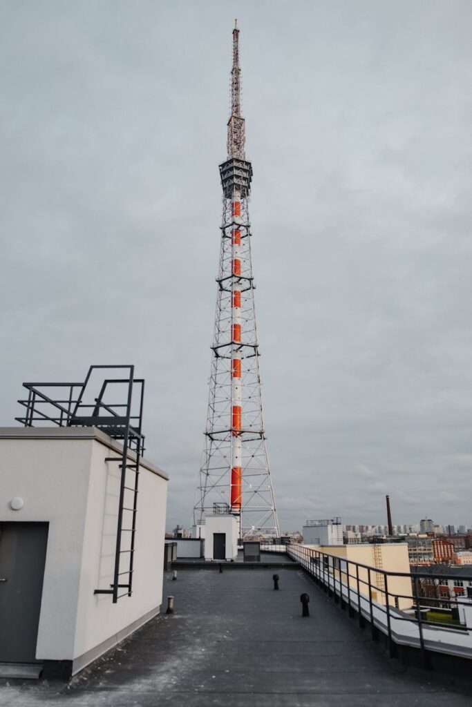 A tall microwave transmission tower with satellite dishes pointing towards a distant city.