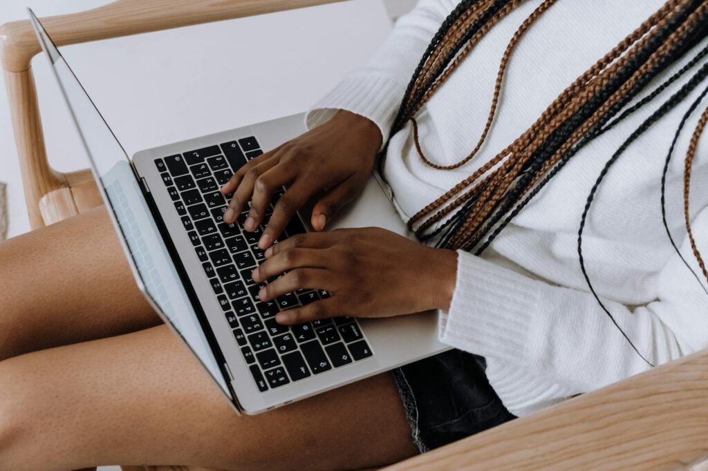 Close-up of a person's hands typing on a laptop keyboard, with a notebook and pen nearby, illustrating freelance work.