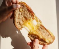 A person with glasses carefully reads the nutrition facts and ingredients list on the back of a food package.