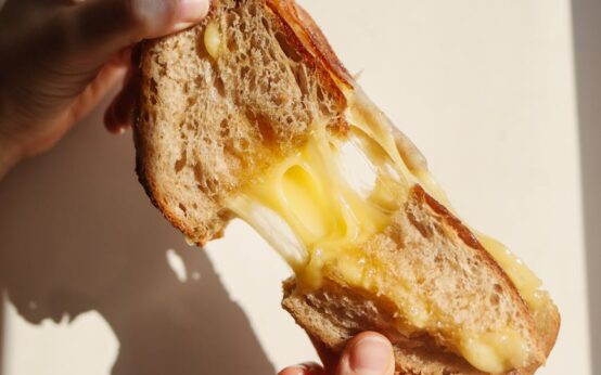 A person with glasses carefully reads the nutrition facts and ingredients list on the back of a food package.