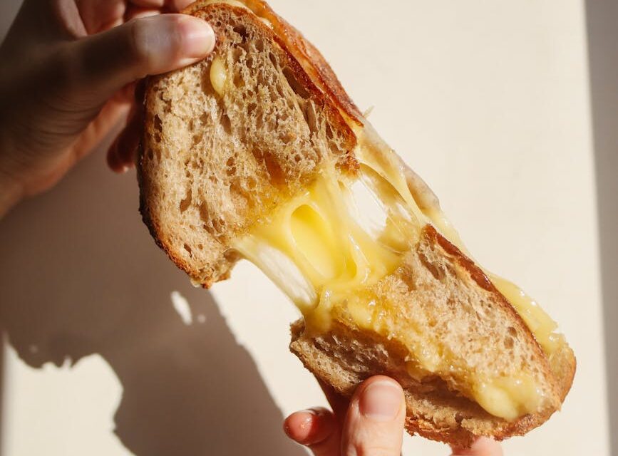 A person with glasses carefully reads the nutrition facts and ingredients list on the back of a food package.