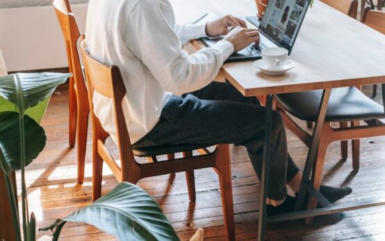 A designer creating a Canva template on a laptop in a cozy home office setting.
