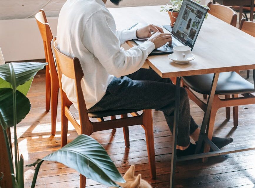 A designer creating a Canva template on a laptop in a cozy home office setting.