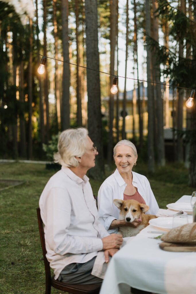 A large, diverse family sharing a meal and conversation at a long wooden table in a beautiful garden setting during their vacation.