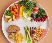 A vibrant, top-down view of various foods that reduce inflammation, including a piece of grilled salmon, a bowl of fresh blueberries, and dark leafy greens.