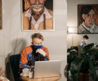 A person sitting at a comfortable home office desk, focused on their laptop while planning an online side hustle.