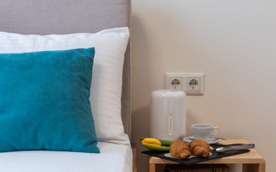 A steaming white mug of chamomile tea with a lemon slice, resting on a wooden bedside table next to a book and a soft lamp.