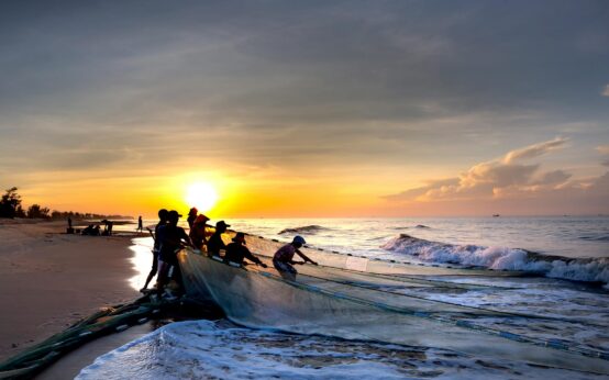 A silhouette of a traditional stilt fisherman in Sri Lanka against a vibrant sunrise over the ocean.
