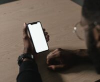 A creator smiling while looking at their smartphone which displays a graph of their earnings.