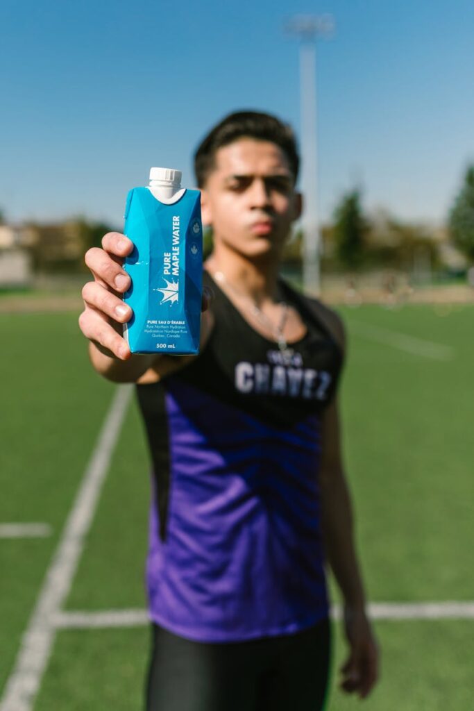 A close-up shot of a person's hand holding a modern, stainless steel reusable water bottle to their lips.