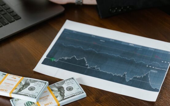 A laptop on a wooden desk with a stack of cash next to it, symbolizing making money online.