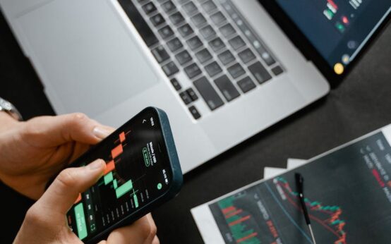 A freelance web developer's desk with a laptop displaying code, a smartphone, and cash.