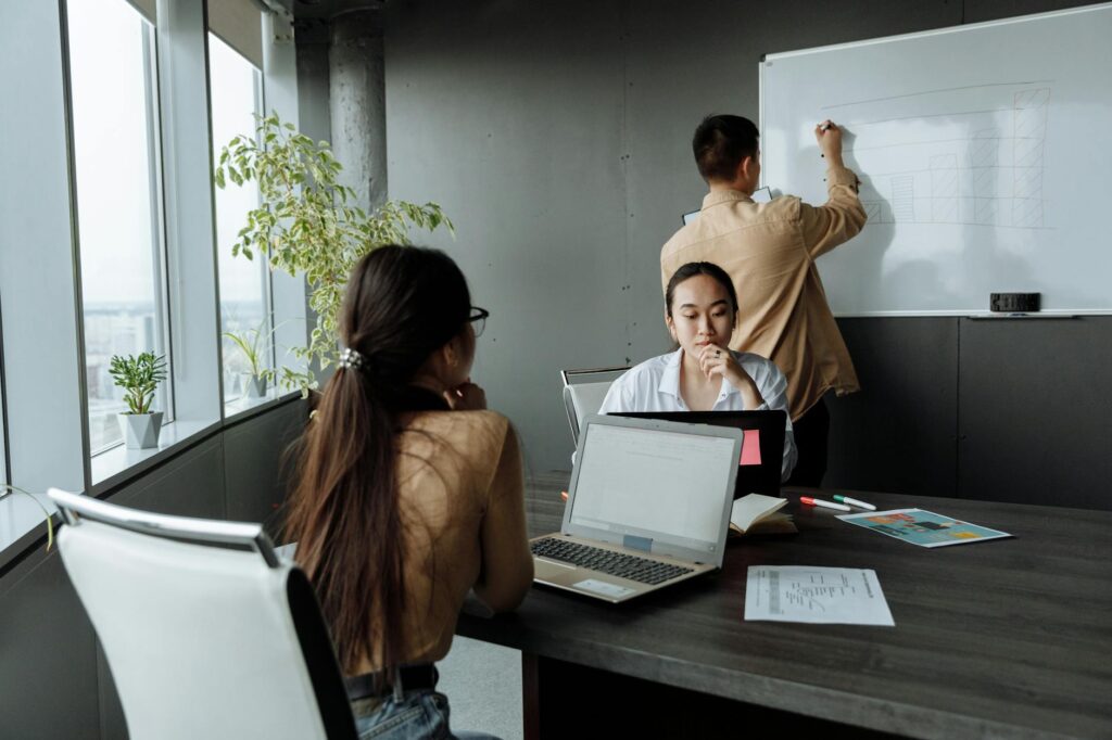 A creative professional writing business ideas on a whiteboard in a bright workspace.