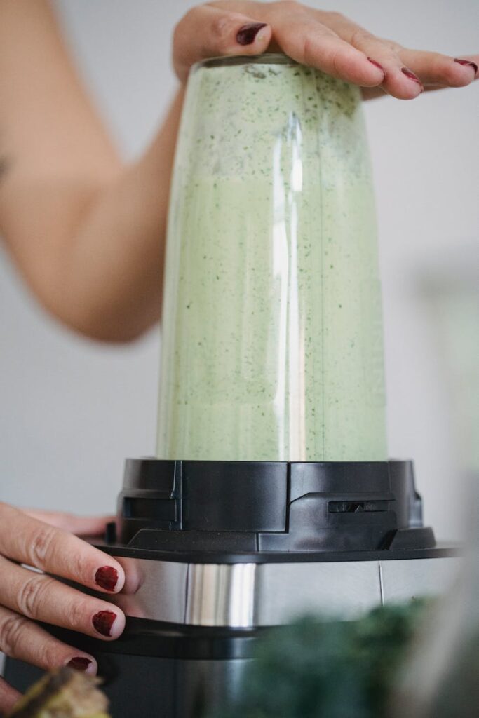 A person holding a glass of a healthy green smoothie, made with superfoods like spinach and kiwi, to boost their immune system.