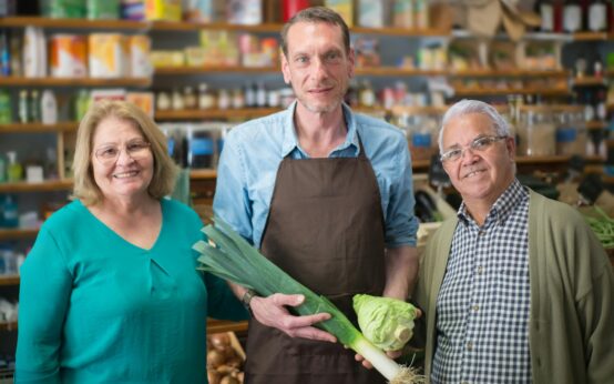 A close-up of a person's hands holding a cereal box and pointing at the nutrition facts label.