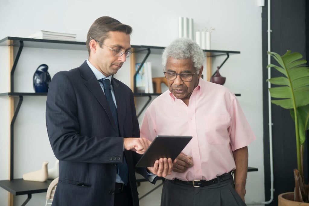 A team of professionals in a modern office looking at a tablet displaying graphs and digital assets.